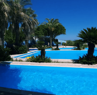 a pool with a blue sky and palm trees in Faliraki Waterpark Rhodes Greece