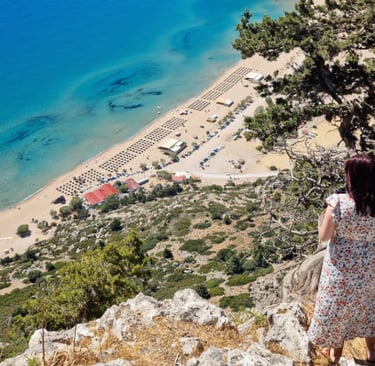 a woman watching tsambika beach from hilltop