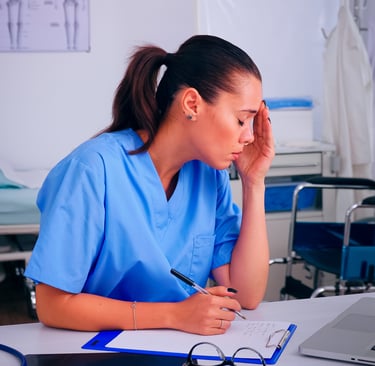 overworked nurse wrinting on clipboard working