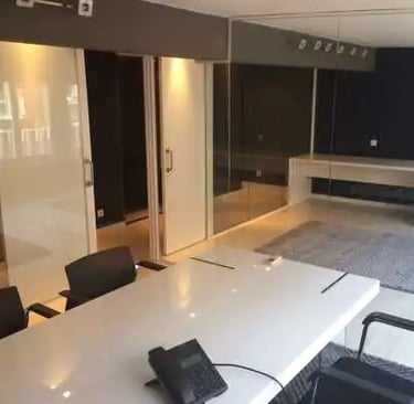 Mampara de oficina en vidrio laminado de espesor 5+5 mm. con puerta de melamina blanca, con luz cenital