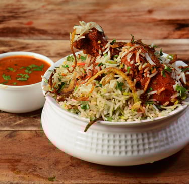 Hyderabadi chicken biryani served with raita, garnished with fried onions and fresh herbs
