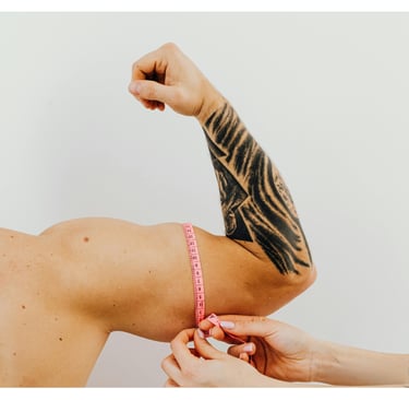 Profissional fazendo medição do bíceps de um homem com uma fita métrica rosa