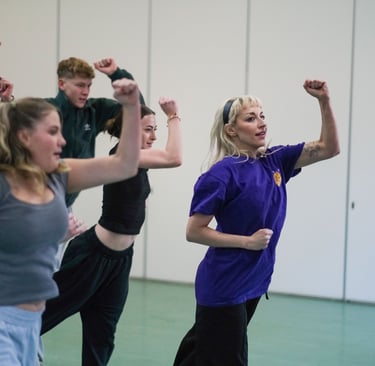 A group of dancers holding their arms up mid dance