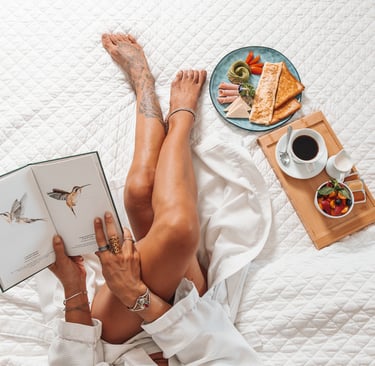 a woman is laying on a bed with a book and a plate of food in her bedroom of a hotel in costa rica