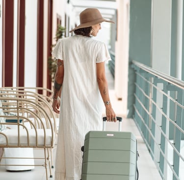 a woman in a white dress and hat, holding a suitcase in a hotel in costa rica