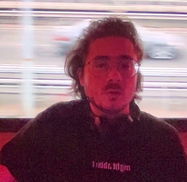 a man with a beard and glasses in front of a tv screen