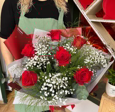 Florist holding a romantic bouquet of red roses and white baby's breath flowers.