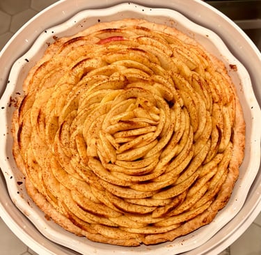 Freshly baked apple tart with thin slices arranged in a rose pattern and sprinkled with cinnamon.