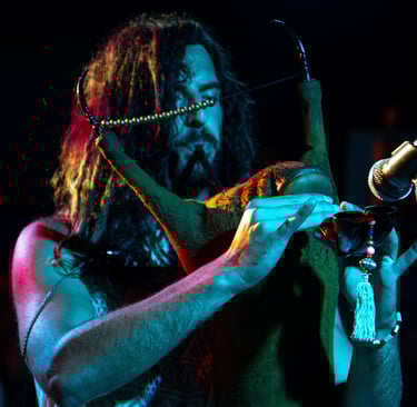 a man with long hair and a beard playing a Tunisian Mezoued