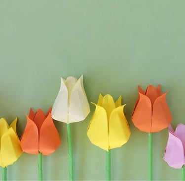 Immaginie di diversi fiori colorati su sfondo verde fatti con la tecnica degli origami
