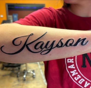 a person with Beautiful script art tattoo on their arm