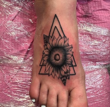 a tattoo style sunflower tattoo on the foot of a woman's foot