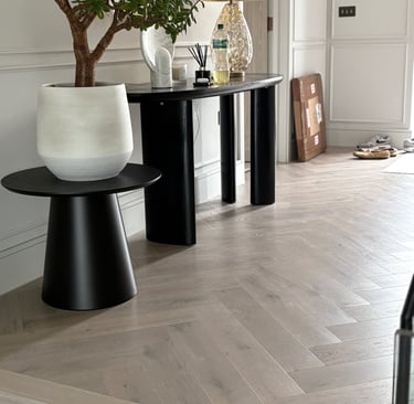 A light oak herringbone floor in a hallway with a step and small tbale