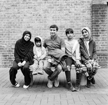 Muslim father and his children sitting on a bench in London