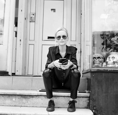Woman sits outside her hair salon taking a break