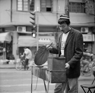 Uighur man in Shanghai sells lamb skewers by the side of the street