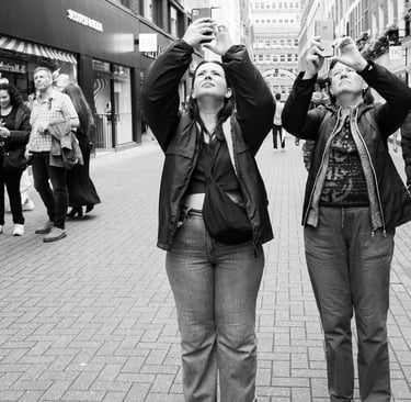 Two female tourists in Carnaby Street London look up towards the sky and simultaneously take photos