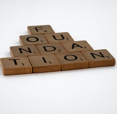 Scrabble letters spelling out the word foundation arranged in a pyramid shape on a white background