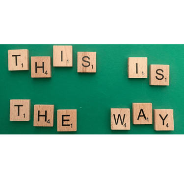 Scrabble tiles spelling out the words this is the way on a green background