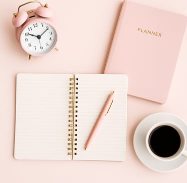 Rosa Schreibtisch Oberfläche mit Wecker, Notizbuch und Kugelschreiber