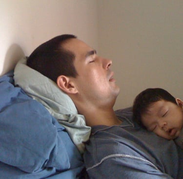 a man sleeping on a bed with a baby