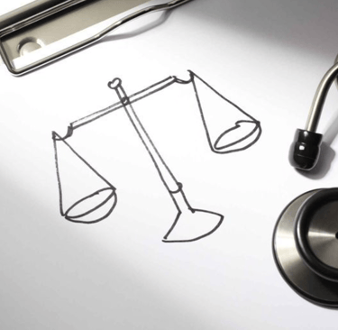 um estetoscópio sobre folha de papel com desenho de balança da justiça