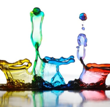 a group of colorful colored liquid paint splashes on a white surface