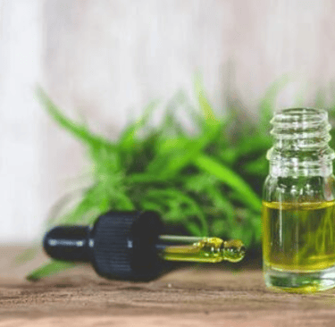 a bottle of oil with a plant in the background