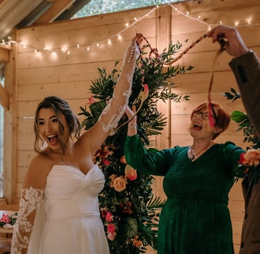 Wedding couple and celebrant smiling and laughing after a handfasting ceremony