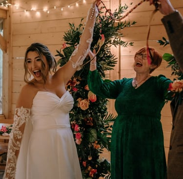 Bride & groom holding up a handfasting ribbon