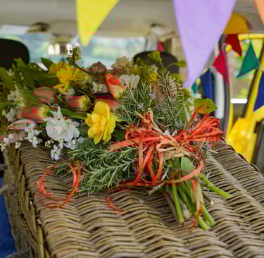 Wicker casket decorated with brightly colour flowers and bunting