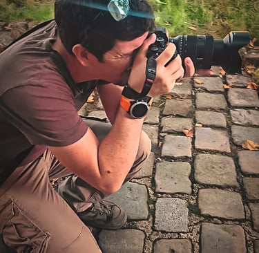 Photographe concentré, accroupi sur des pavés, appareil photo à la main, capturant une scène avec précision et passion