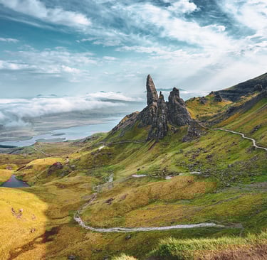 L'Old Man of Storr se dresse majestueusement au milieu des collines verdoyantes de l'île de Skye, sous un ciel dramatique.
