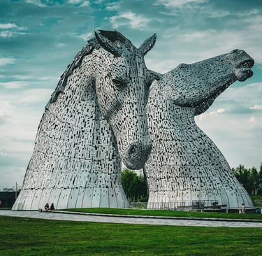 Les Kelpies, sculptures géantes de têtes de chevaux en acier, s'élèvent majestueusement sur un fond de ciel nuageux.