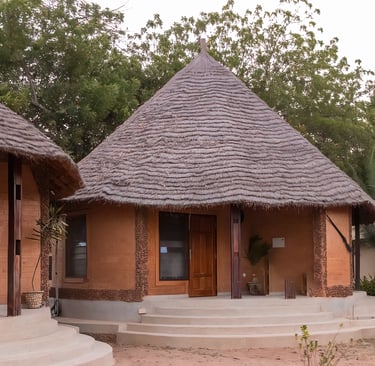 A scenic view of Tendaba Camp, featuring traditional thatched-roof huts and safari tents nestled alo