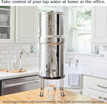Berkey stainless steel countertop gravity water filter system on a wooden stand in a bright kitchen.