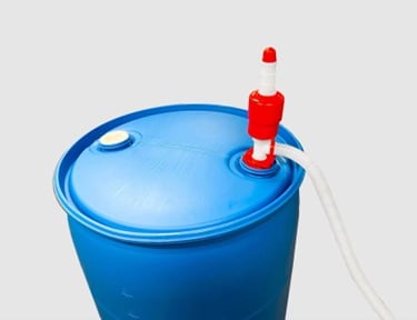 Manual red and white siphon pump attached to a 55-gallon blue plastic water storage drum.