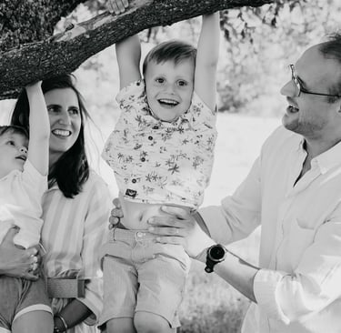Enfants jouant à se suspendre à un arbre avec l’aide de leurs parents – séance photo de famille Gard