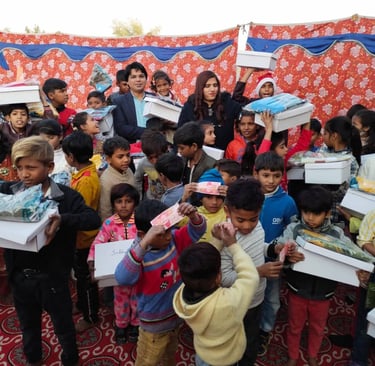 A group of children receiving gift boxes and donations during a charity event for humanitarian aid.