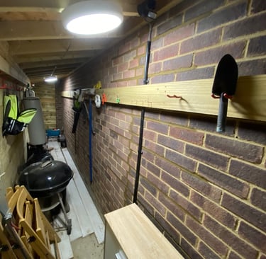 Organized garden stoe orage shed with wall-mounted tool racks, hand trowel, and kettlen brick walls.