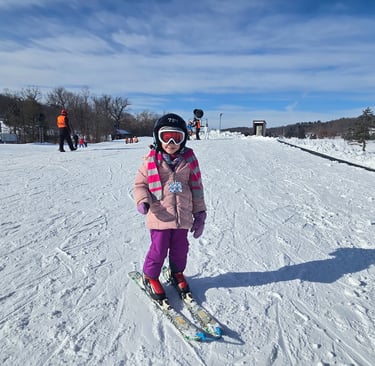 IMage of young girl with pink coat, purple pants, black helmet on skis