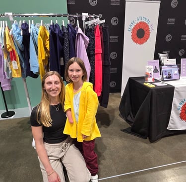 Image of young girl and woman in front of rack of clothing