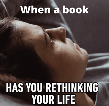 a woman laying on a couch with a book on it