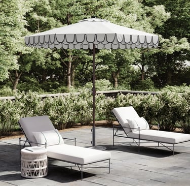 White scalloped patio umbrella with two lounge chairs on a stone terrace for outdoor luxury living.