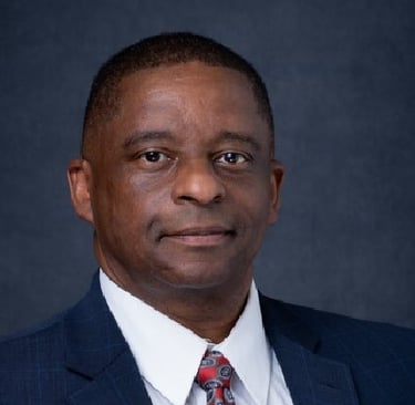 Elder Mark T. Stewart in a suit and tie with a red tie