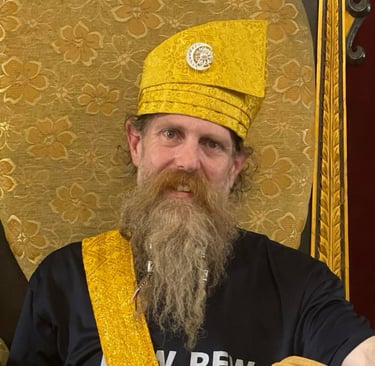Ki Joko Moro seated on a golden chair wearing golden Indonesian ceremonial hat and sarong