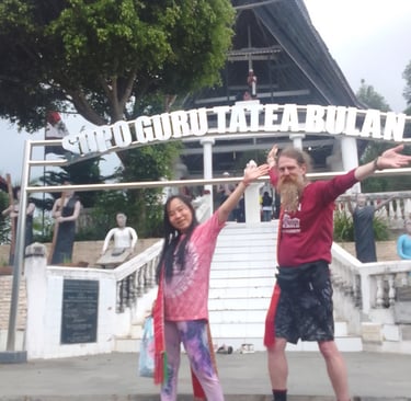a woman and a man are joyful and smiling in front of an ancient shrine site in Sumatra