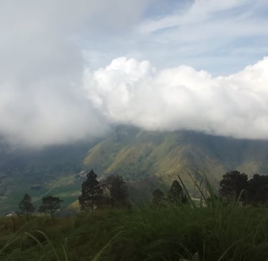 On a mountain top overlooking a valley with clouds hiding the peaks of other mountains
