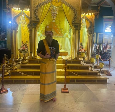 a man at Istana Maimun in traditional Indonesian ceremonial hat and sarong with a kris