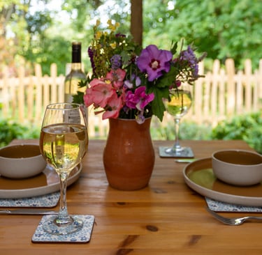 a table with a vase of flowers and a glass of wine